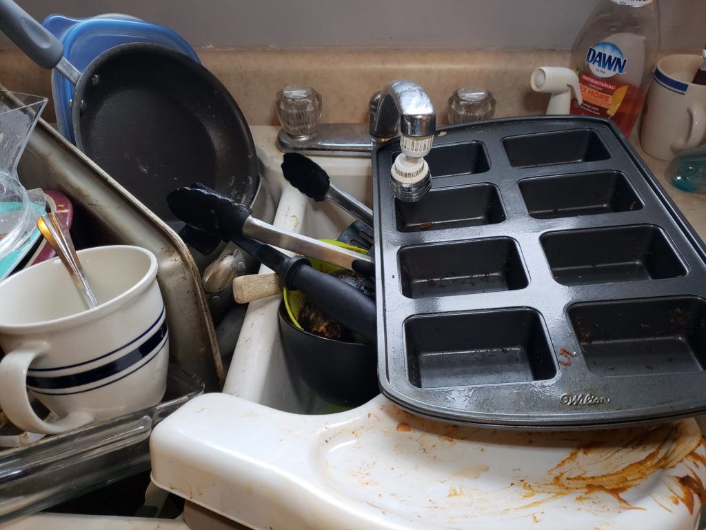 dirty dishes piled into and around a kitchen sink