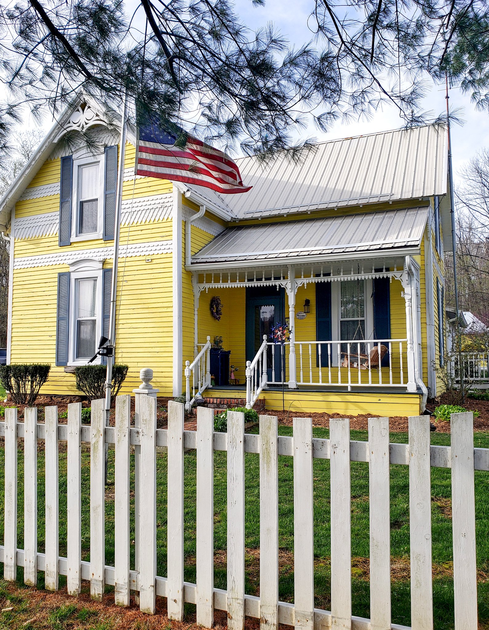 Large yellow and white two story house with a white picket fence makes up the first section of the 1875 Homestead Bed and Breakfast