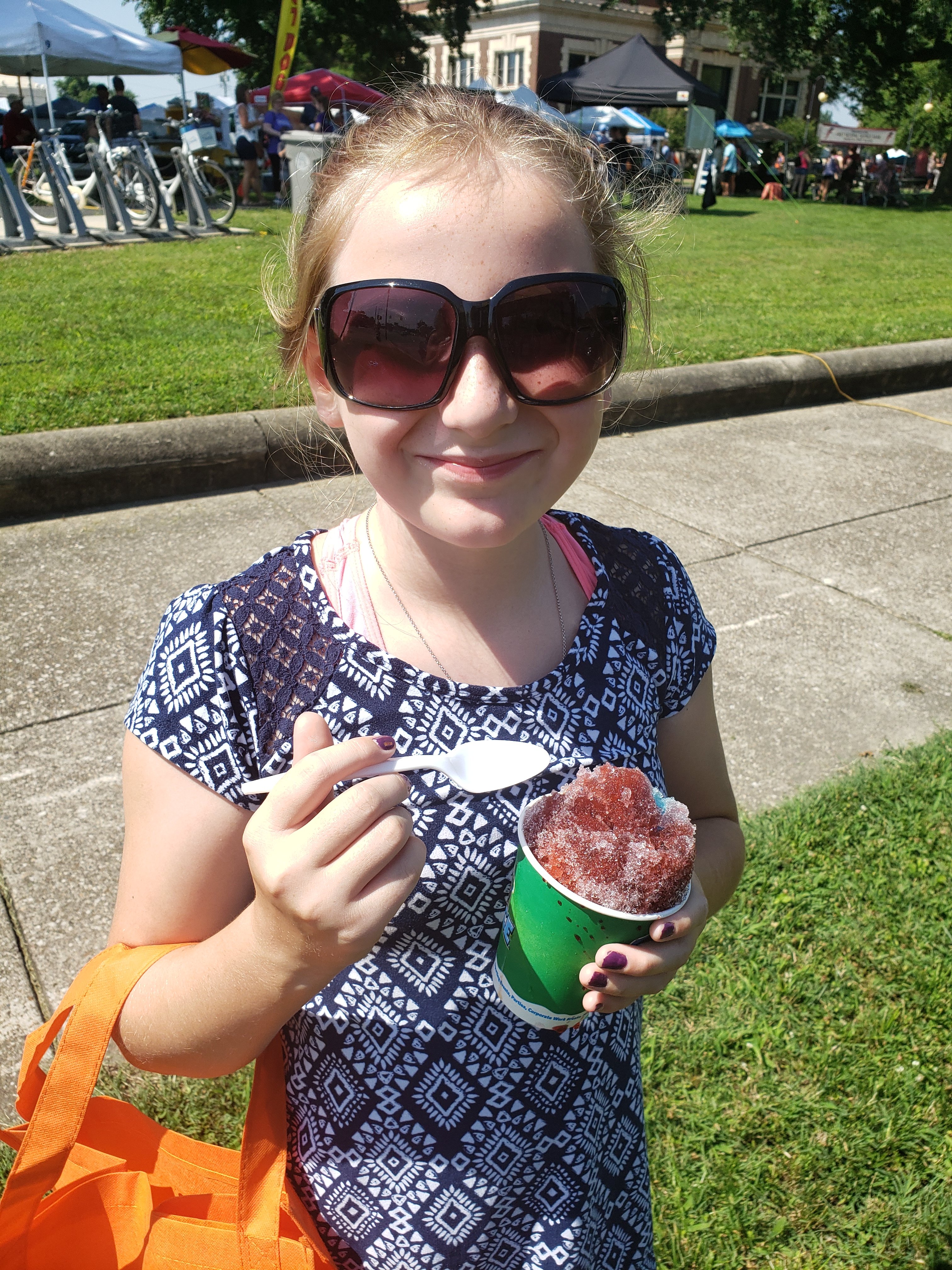 Little girl in sunglasses smiling with a snowcone free summertime activities for kids