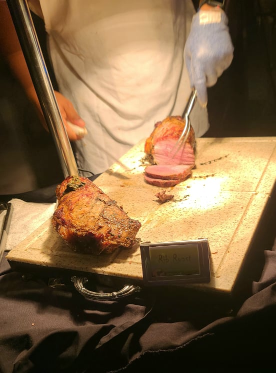 someone slicing rib roast on wooden cutting board