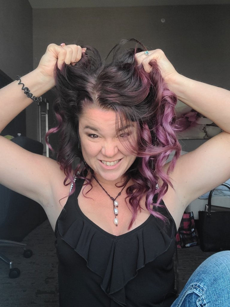 woman with brown and pink curly hair, pulling her hair in frustration