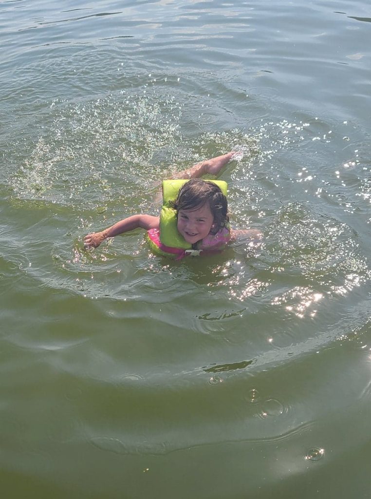 a child wearing a life jacket swimming 