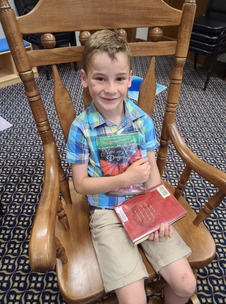 a boy sitting in a rocking chair holding two books