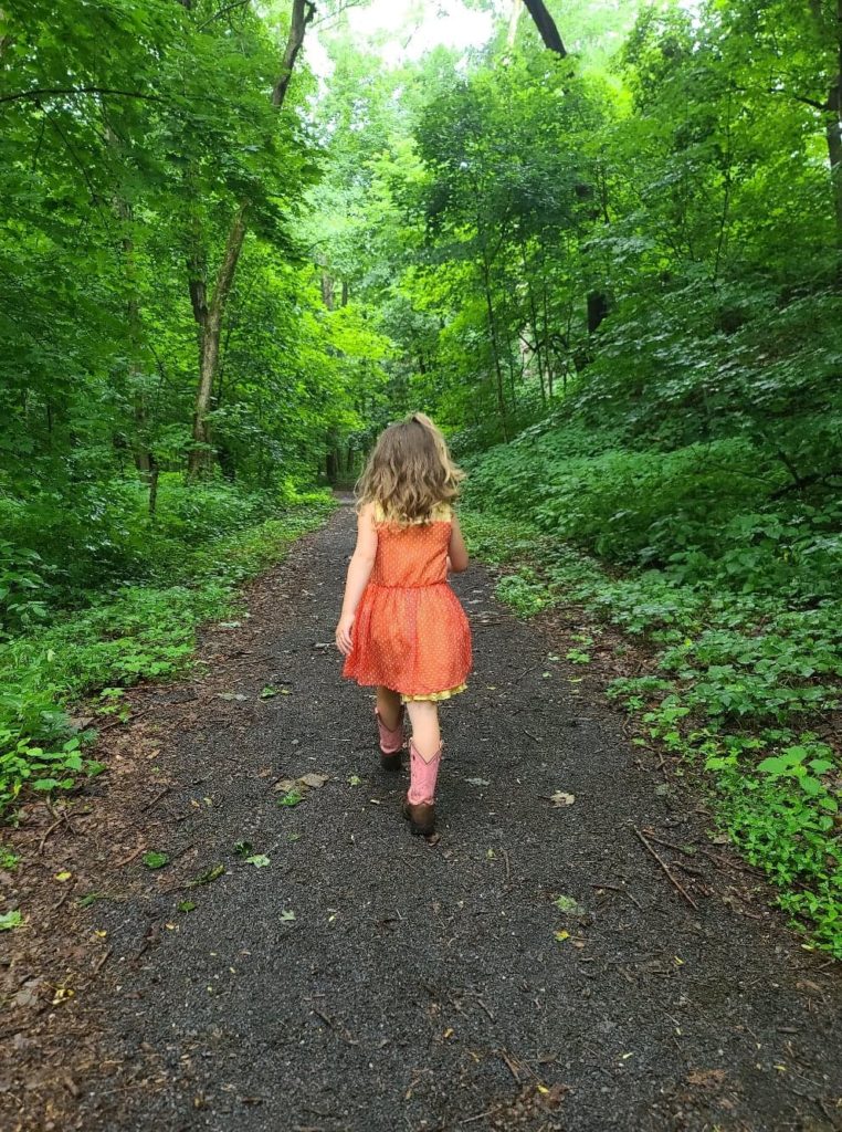 girls in an orange dress walking a path in the woods free summertime activities for kids