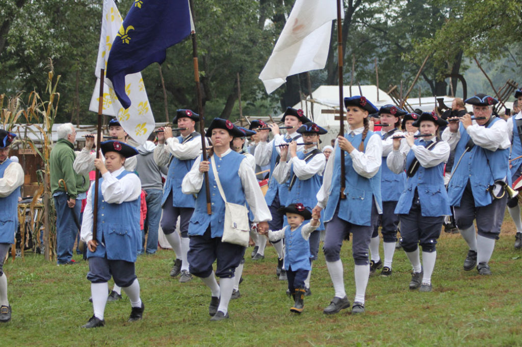 reenactment people in parade with flags and flutes