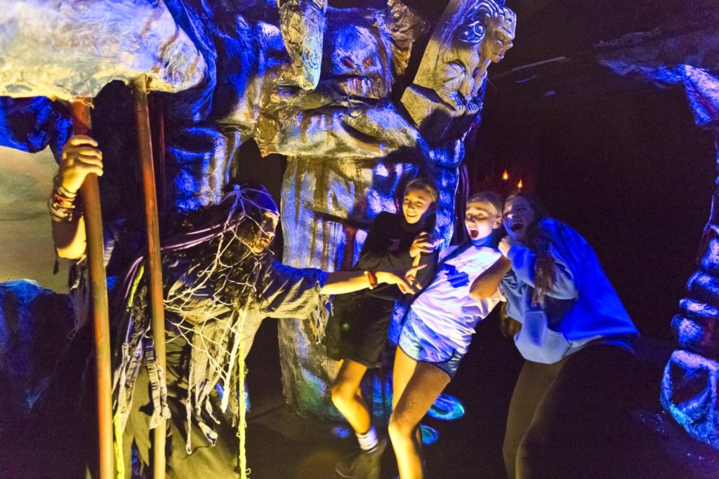 three teen girls being scared in a spooky setting