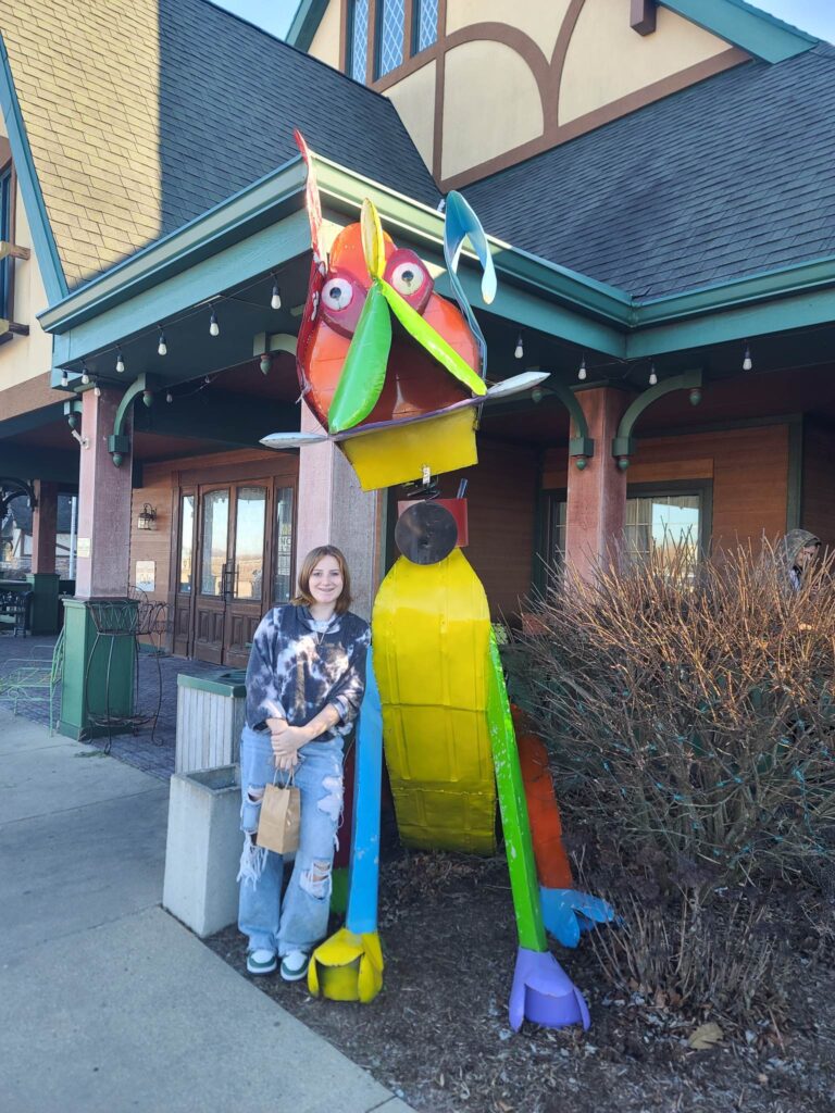 young girl standing beside a large dog sculpture outside of Warm Glow Candle Outlet