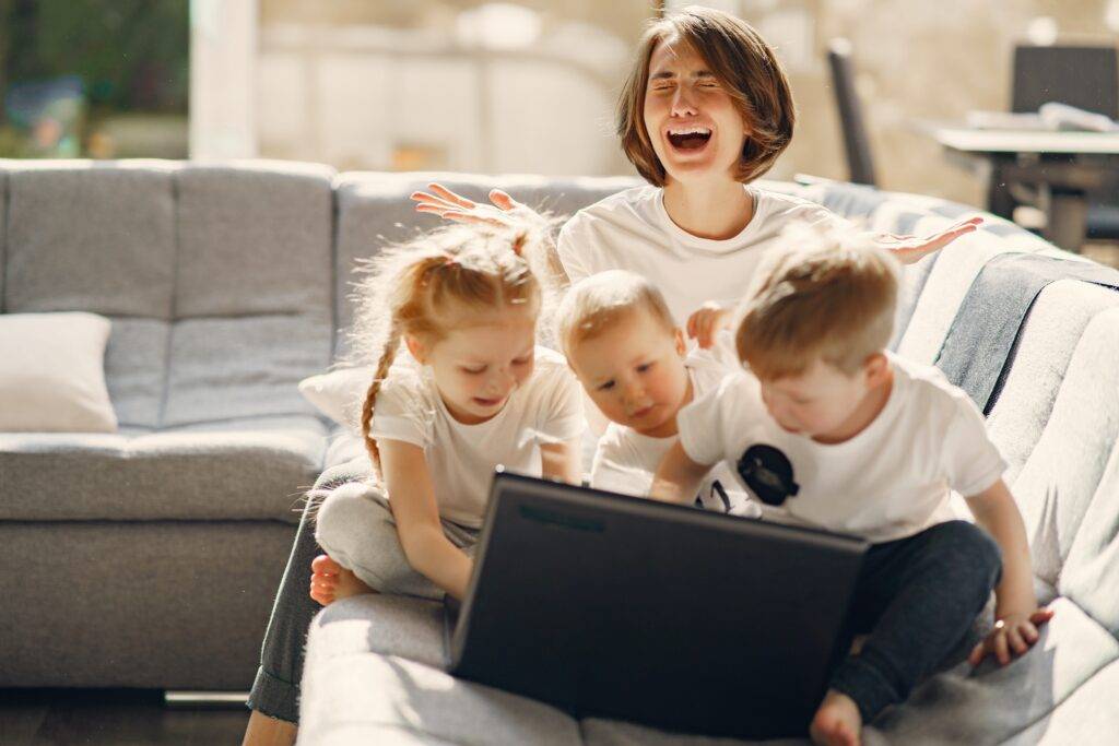 Stressed mom working from home with three children who have taken over her laptop