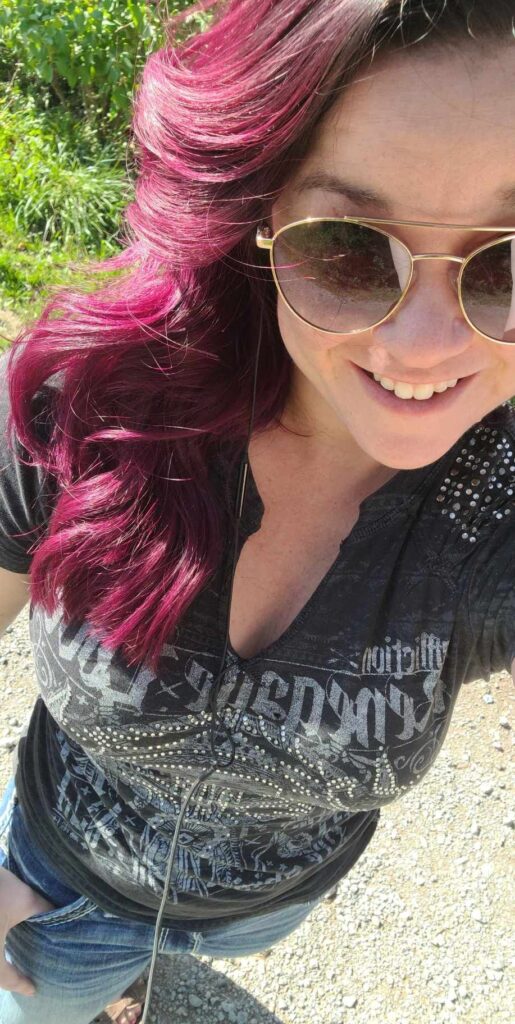 Woman with deep magenta hair and aviator sunglasses with a confident smile on her face.  embrace your true self and embrace being too much